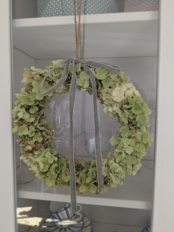 Getrocknete Blumen in einer Glasvase neben weißen Schalen